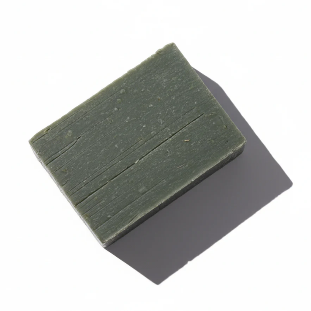 Handcrafted Pine Moss & Loofah soap bar from LG Apothecary Co. with a rich, forest-green hue and textured finish resting on a white surface.