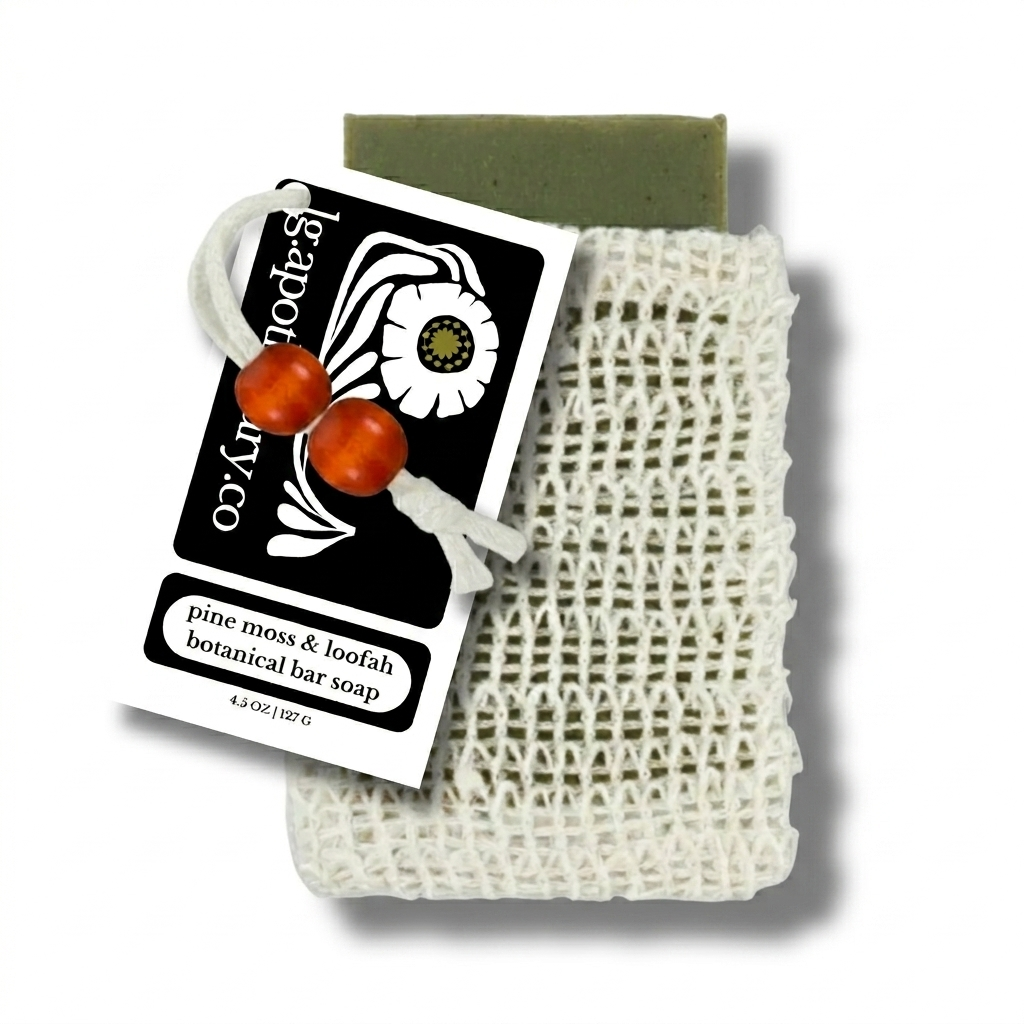 Restorative Pine Moss and Loofah soap bar from LG Apothecary Co partially tucked into a natural sisal bag, resting on a clean, minimal surface.