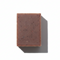 LG Apothecary Co. Vanilla Oatmeal Botanical Bar Soap, featuring a dense, chocolate-brown bar with visible oat flecks and a clean, straight-cut edge, resting on a crisp white background with a sharp, artistic shadow.